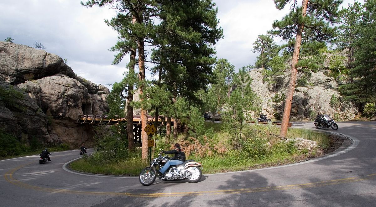 A motorcycle rounding a wooden pigtail bridge on Iron Mountain Road